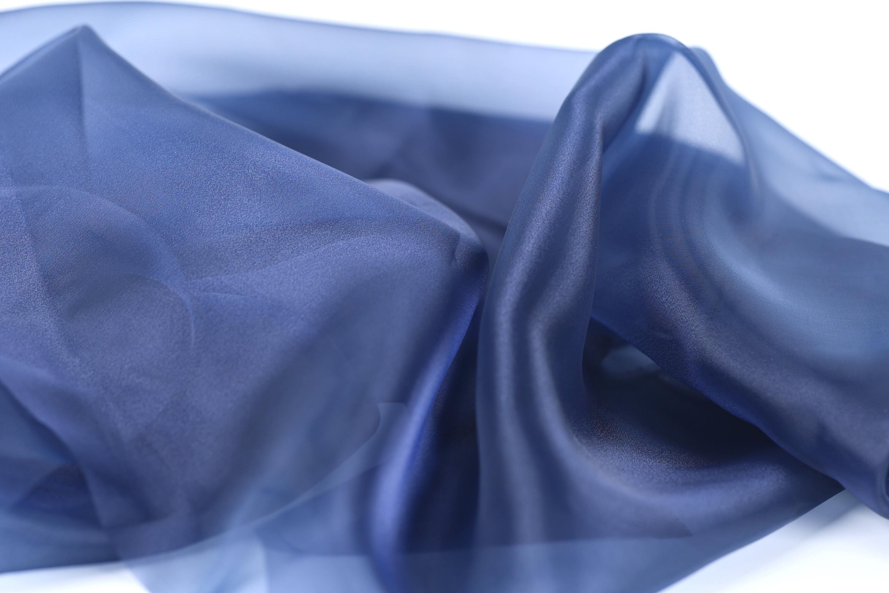 a close-up view of a blue fabric, possibly silk or chiffon, with a smooth and shiny texture.