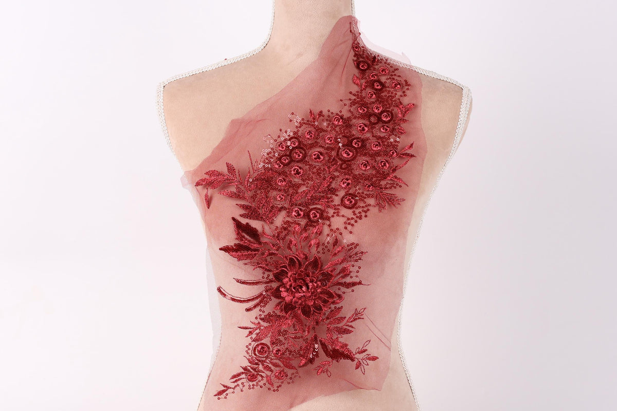 A mannequin wearing a red floral dress with a sheer, tulle-like fabric.