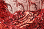 a close-up view of a red fabric with a pattern of sequins and beads, creating a visually striking and intricate design.
