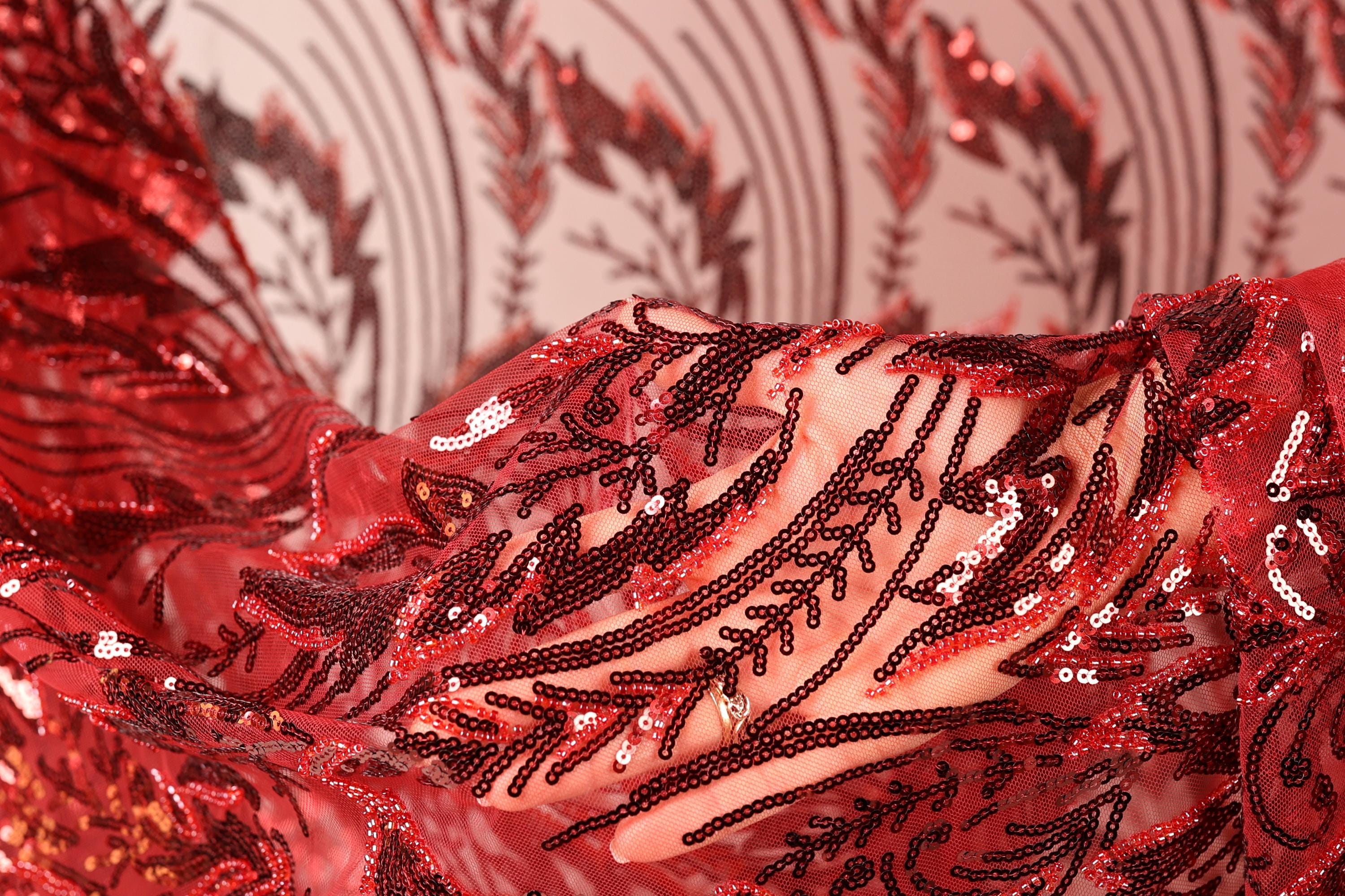 a close-up view of a red fabric with a pattern of sequins and beads, creating a visually striking and intricate design.
