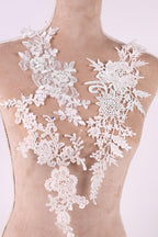 A mannequin wearing a dress with intricate white lace appliques on the neckline and back.