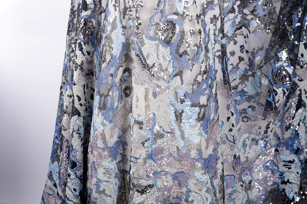 a close-up view of a fabric with a pattern of blue and silver sequins, creating a visually striking and intricate design.