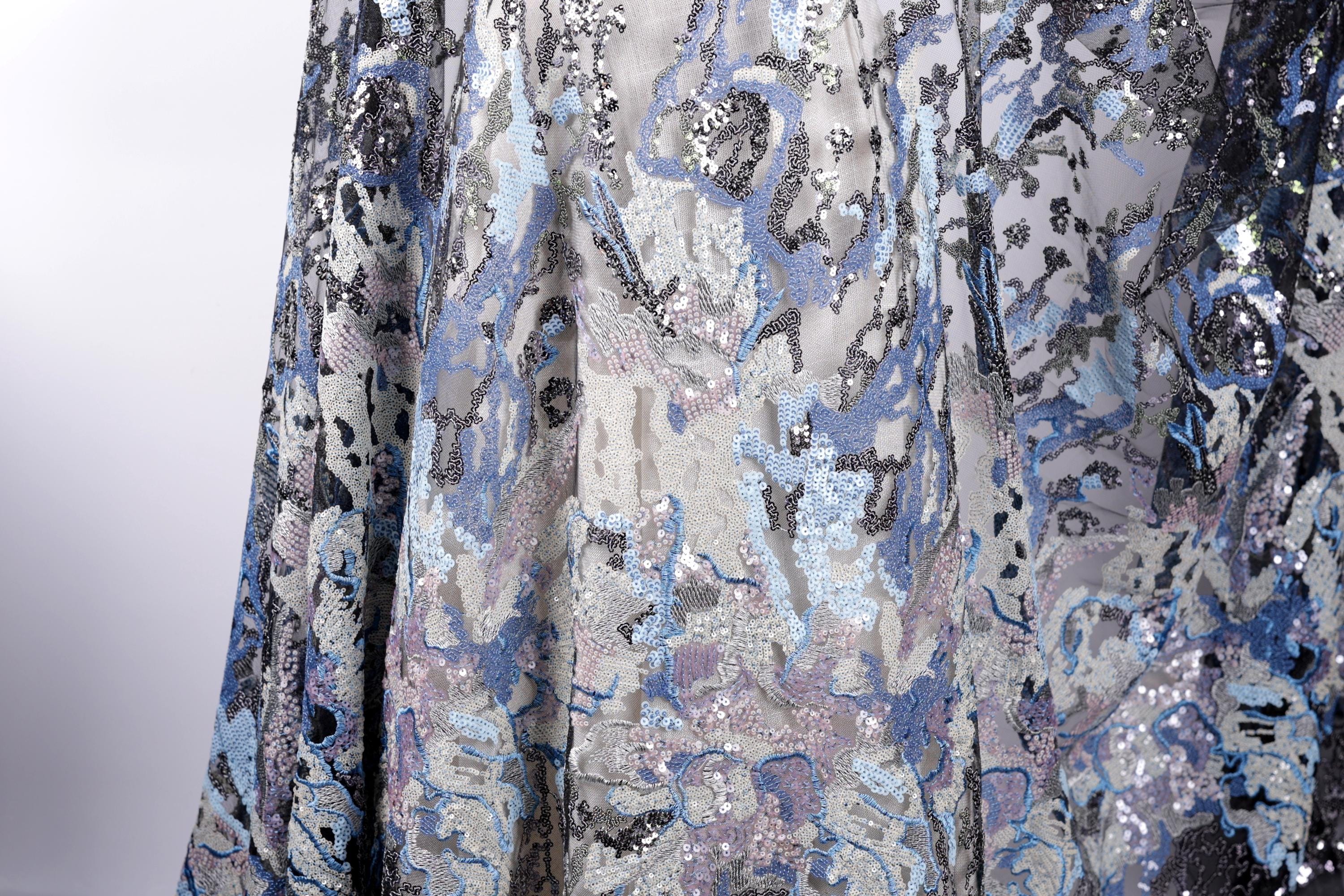 a close-up view of a fabric with a pattern of blue and silver sequins, creating a visually striking and intricate design.