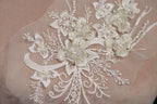 a close-up view of a delicate, intricate piece of lace or fabric adorned with a floral pattern. The lace features numerous small flowers and leaves, creating a visually appealing and delicate design.
