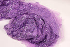 a close-up view of a piece of purple fabric with a glittery, sequined texture.