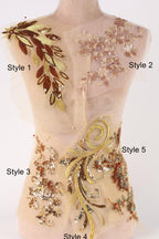 A mannequin with a beige dress and various gold and brown embroidered designs on it, including floral and leaf patterns.