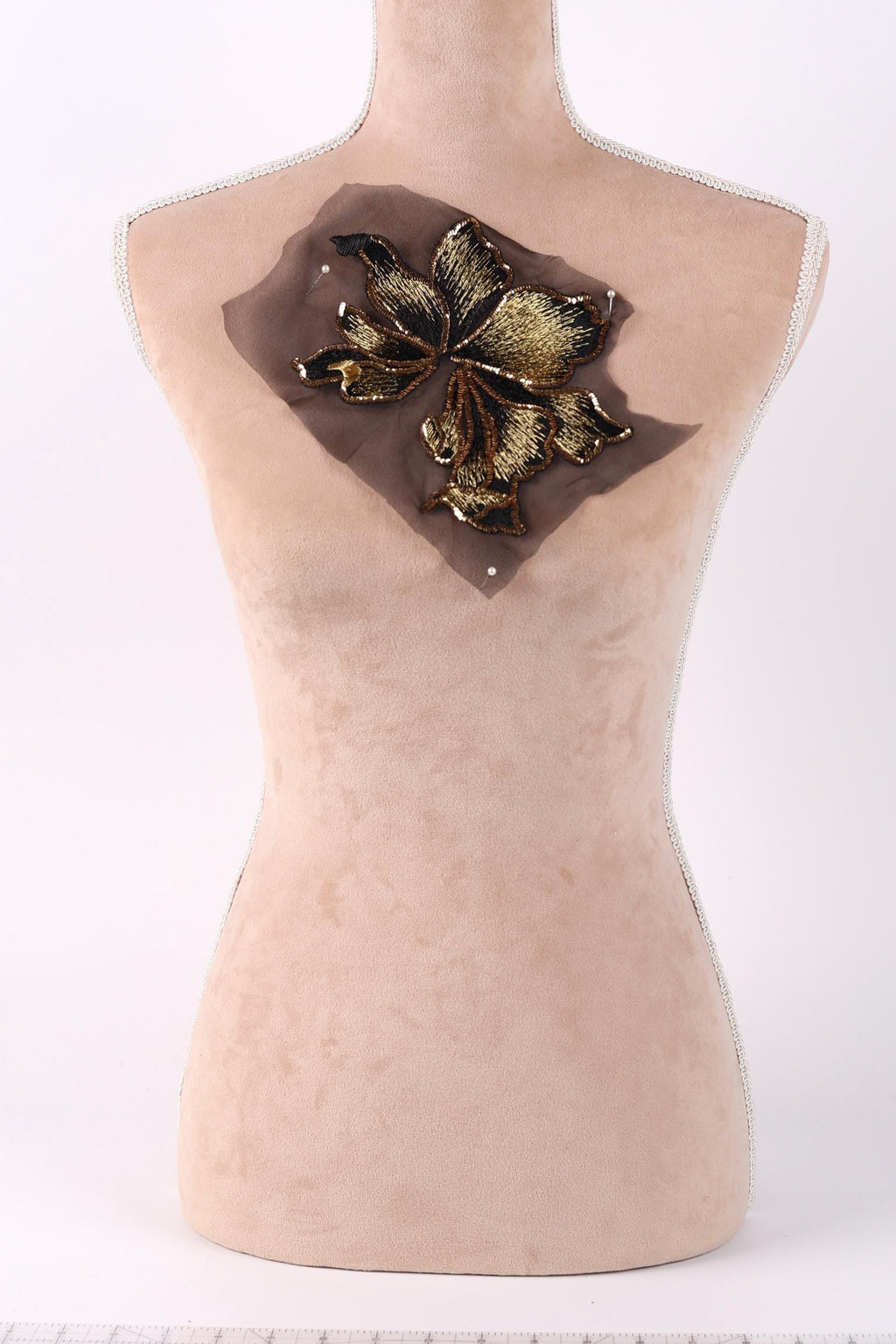 a mannequin with a decorative flower embroidered on its bust.