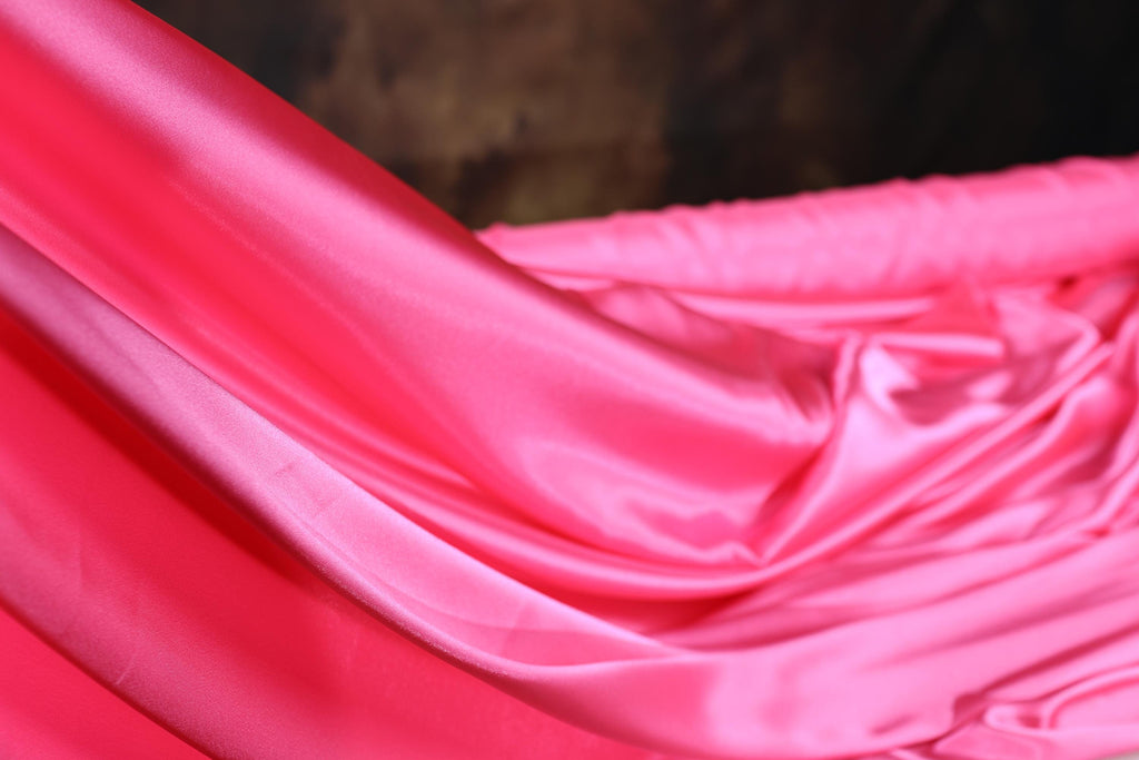 a pink fabric is draped over a bed