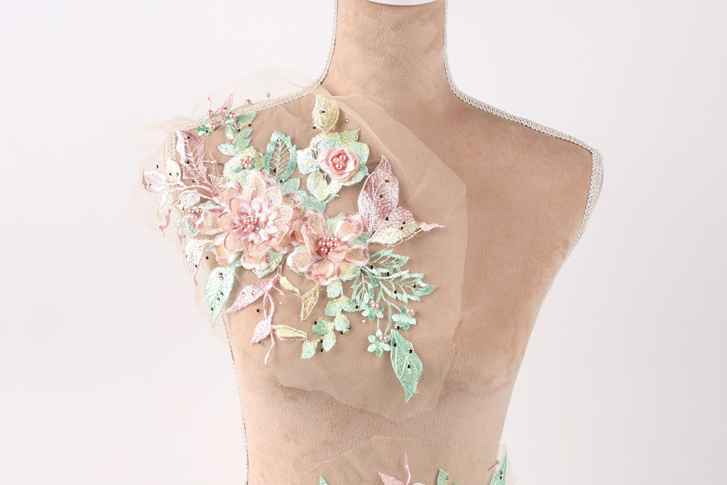 A mannequin with a floral design on its shoulder, featuring pink and green flowers and leaves.