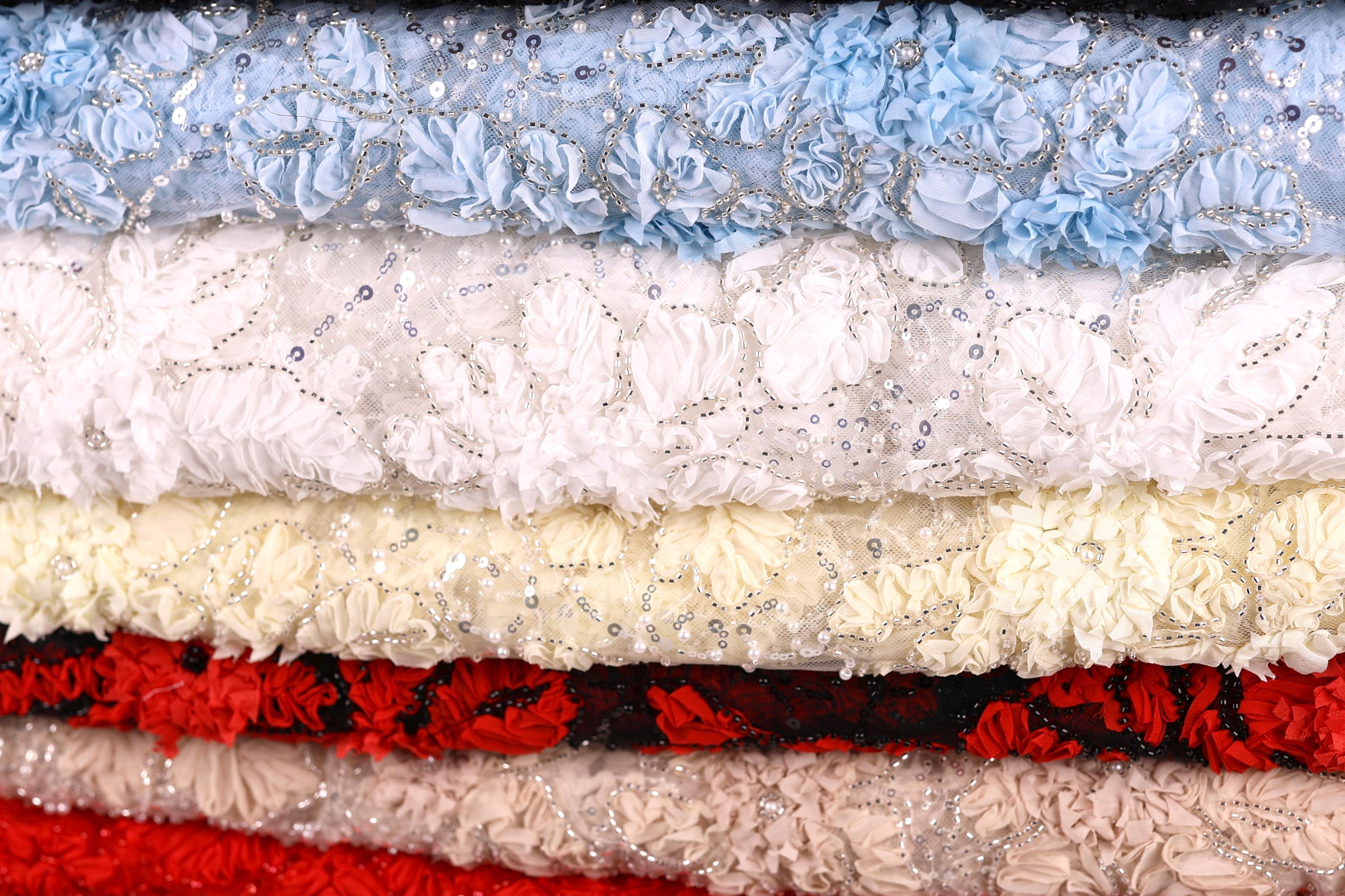 A close-up image of a stack of fabric swatches, featuring a variety of colors and patterns, including white, red, and blue.