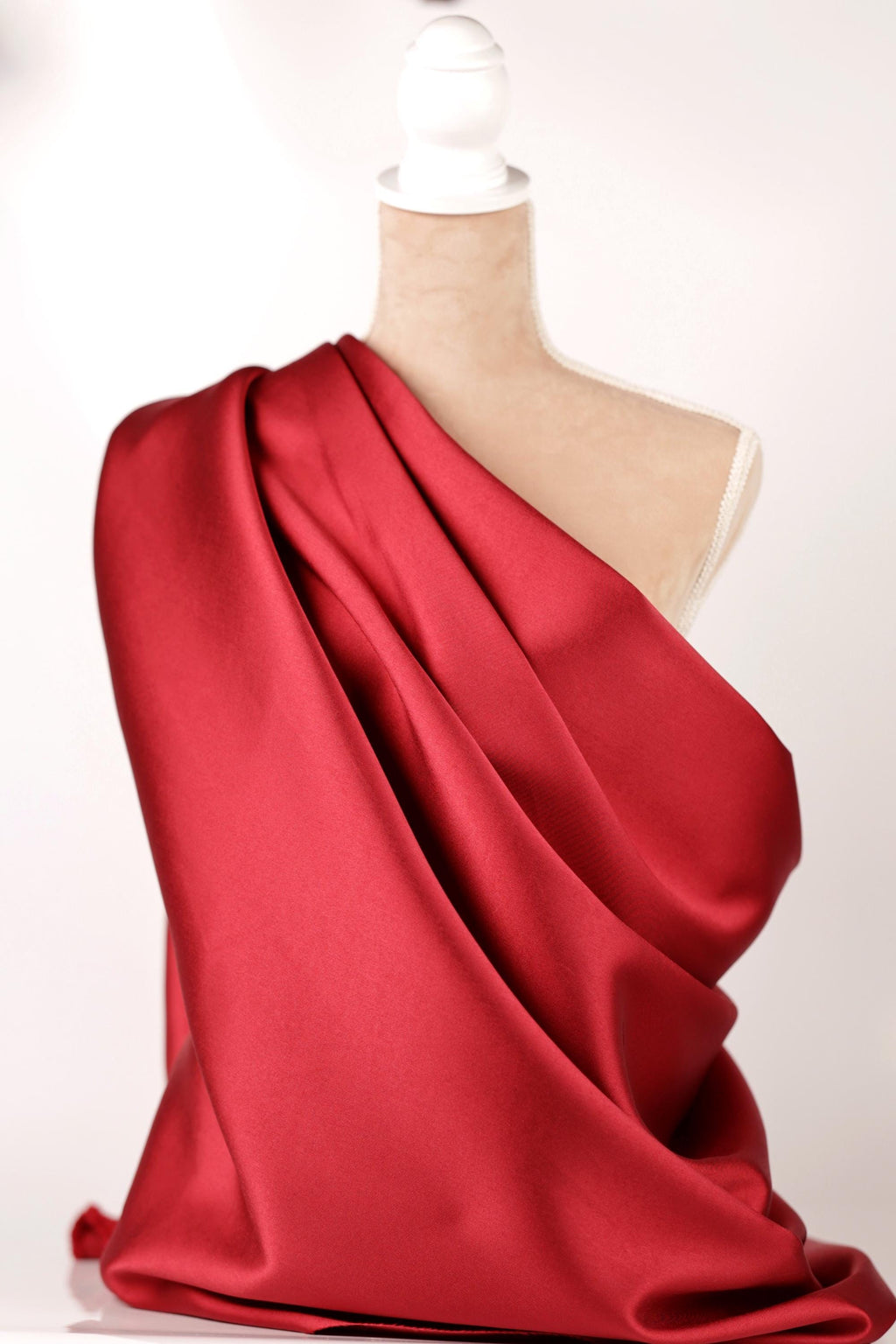 A mannequin is draped in a vibrant red satin fabric, creating a striking visual display.