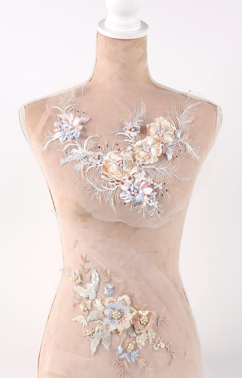 A mannequin wearing a beige dress with intricate floral embroidery on the bust and waist areas.