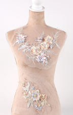 A mannequin wearing a beige dress with intricate floral embroidery on the bust and waist areas.