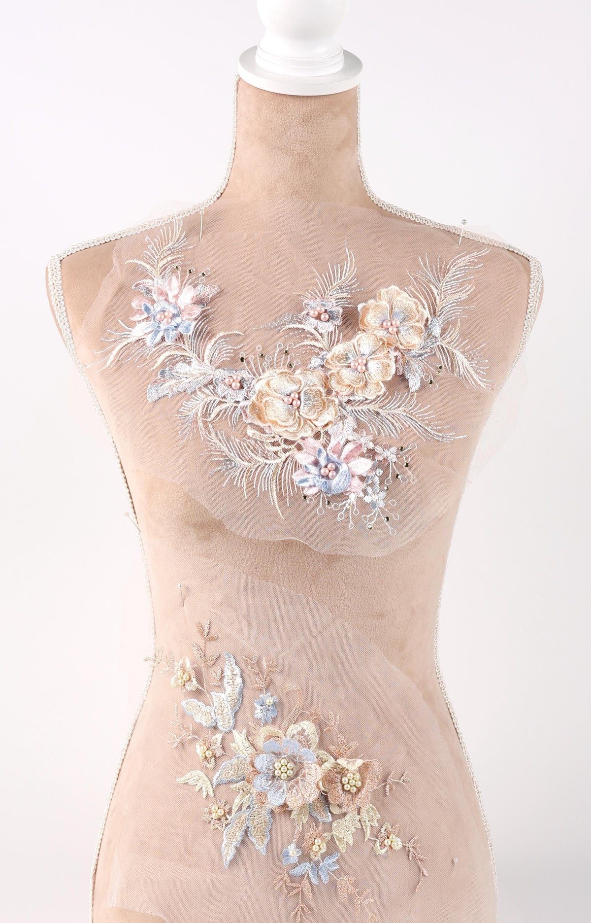 A mannequin wearing a beige dress with intricate floral embroidery on the bust and waist areas.