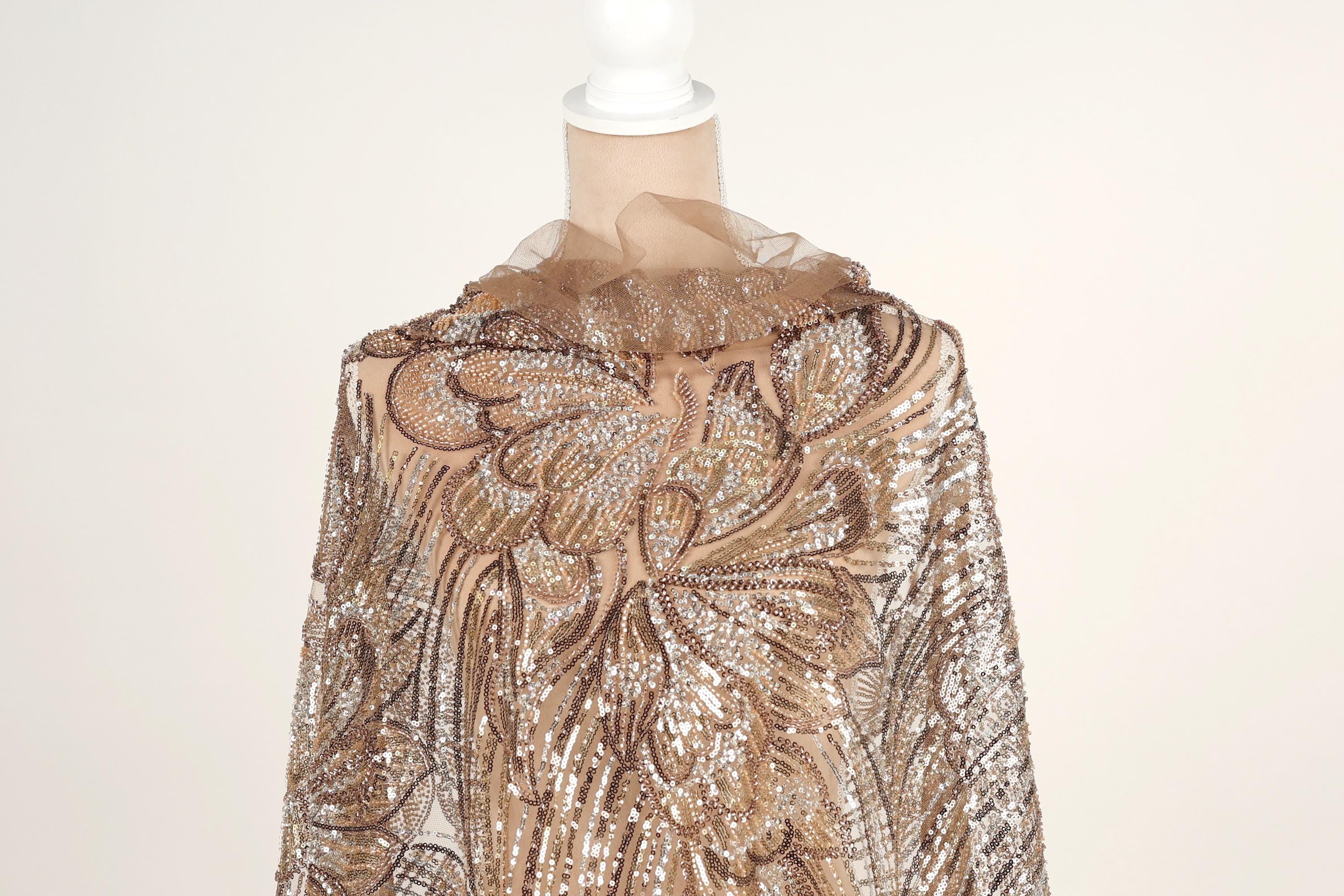 A mannequin wearing a gold and brown sequined dress with a ruffled collar.