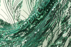 The image is a close-up view of a fabric with a green sequin pattern, featuring a repeating design of green leaves and lines.