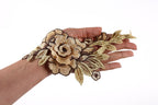 A hand holding a decorative piece of embroidered fabric with a flower design.
