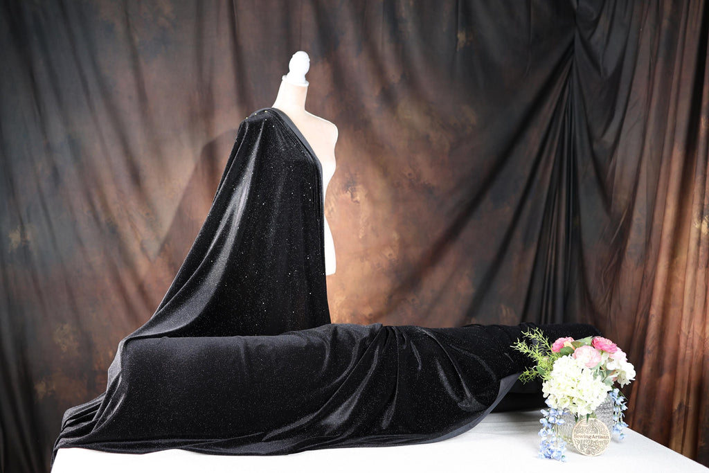 a mannequin dressed in a black cloak and a vase of flowers