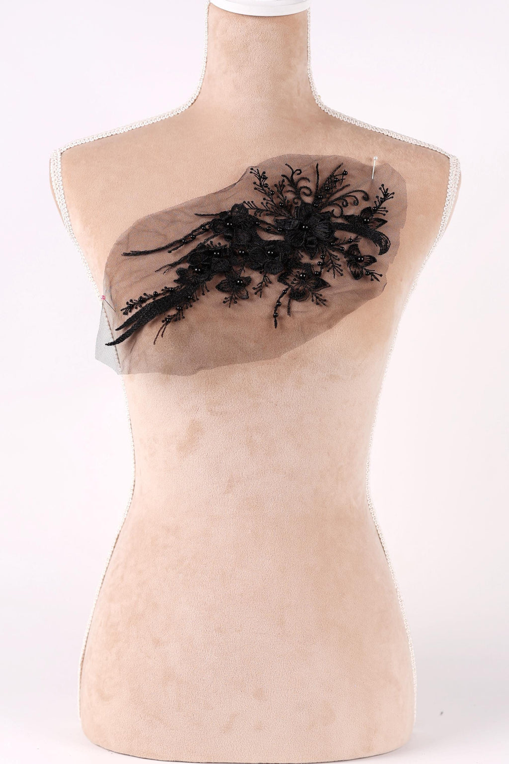 A mannequin with a beige body and a black lace design on its chest.