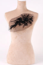 A mannequin with a beige body and a black lace design on its chest.
