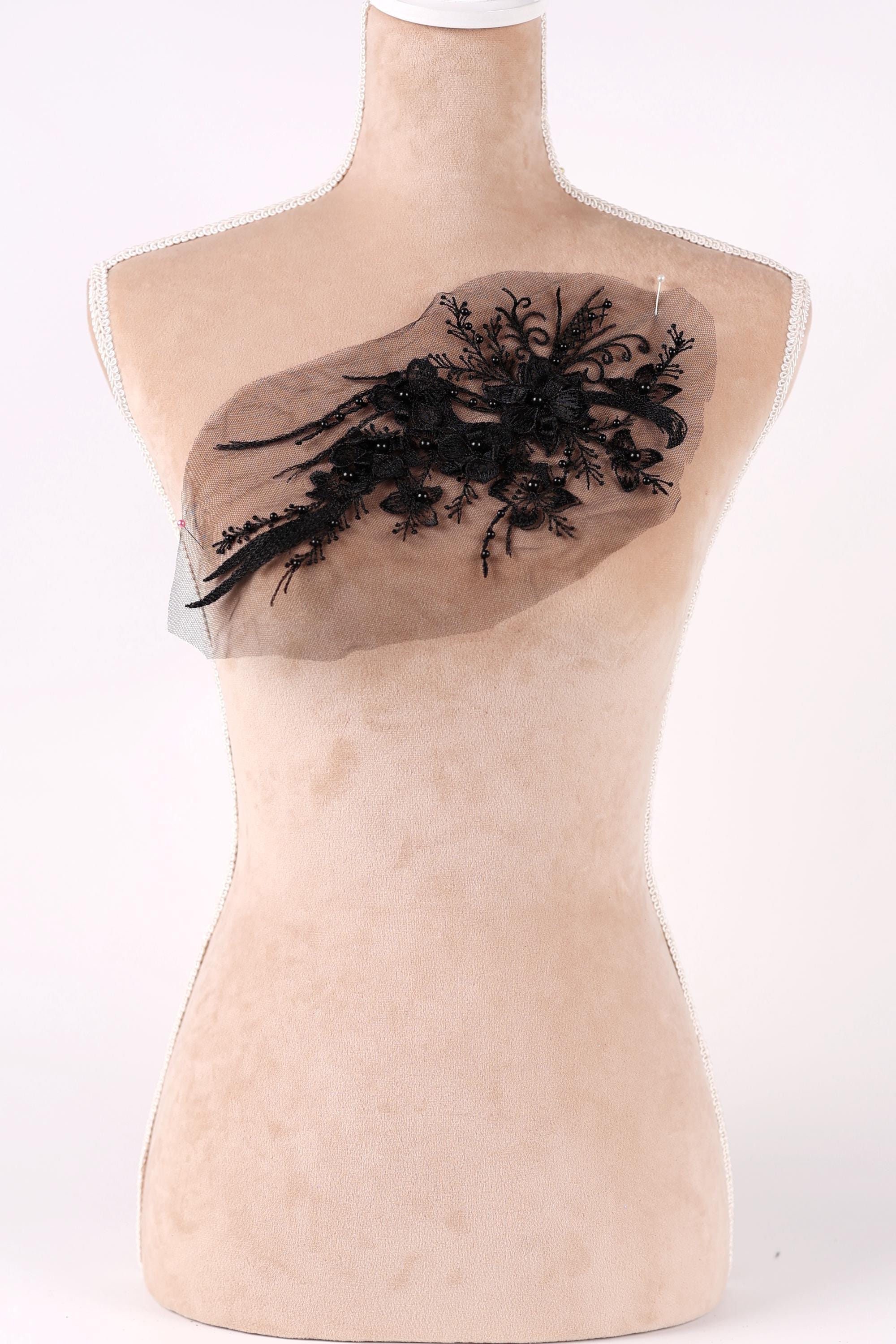 A mannequin with a beige body and a black lace design on its chest.