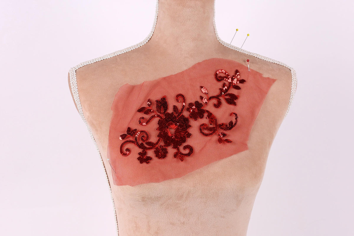 a mannequin with a red fabric piece on its chest, featuring a floral design with red sequins.
