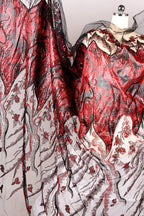 a close-up view of a fabric with a striking red and black pattern, including a mix of sequins and floral designs. The fabric appears to be a sheer material, with a black and white color scheme. The image does not contain any text or other discernible objects or actions.