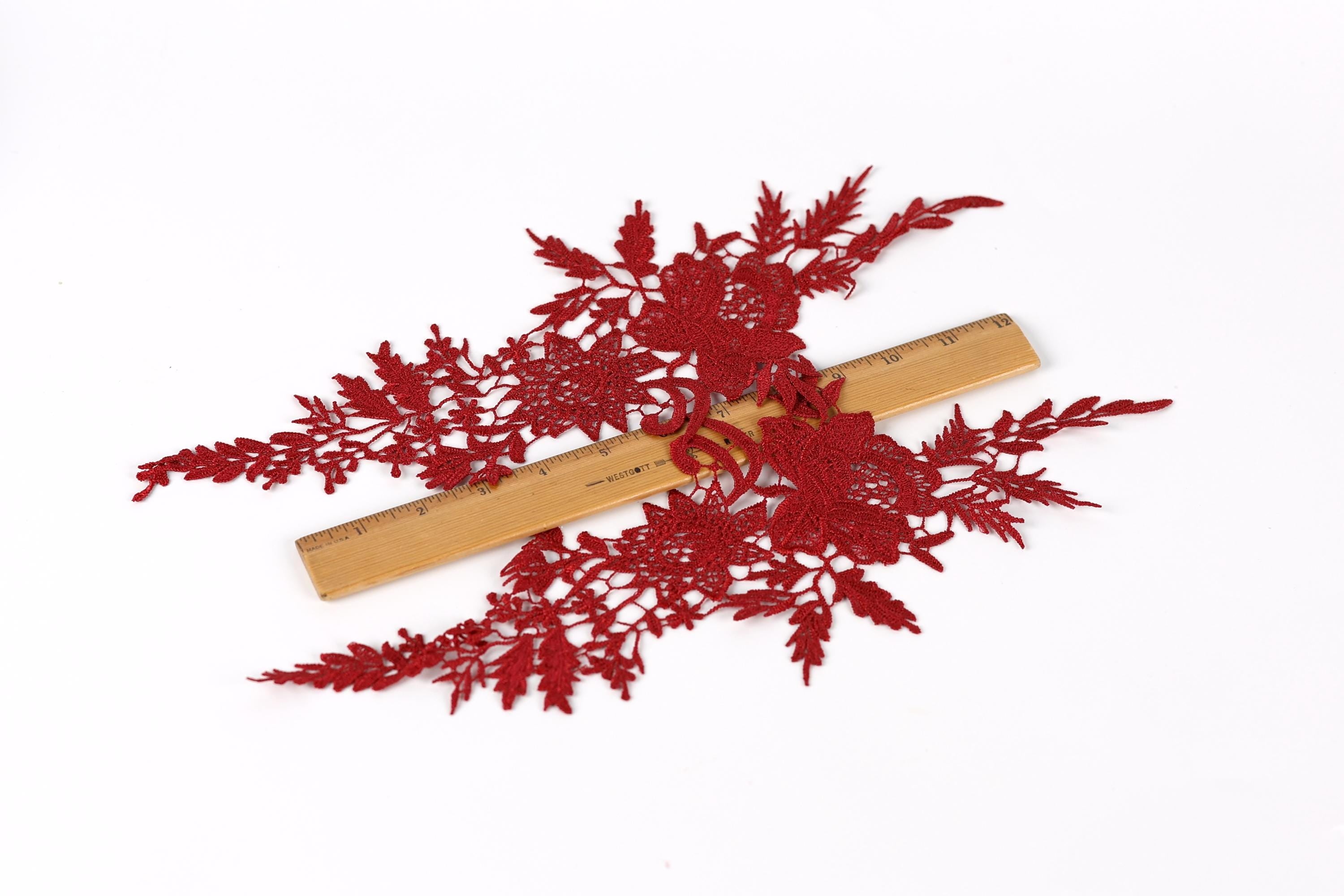 a close-up view of red embroidered fabric with intricate floral patterns, laid out on a white background.