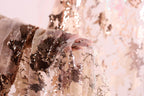 A close-up view of a hand holding a piece of fabric with a floral pattern, featuring a mix of brown and white colors.