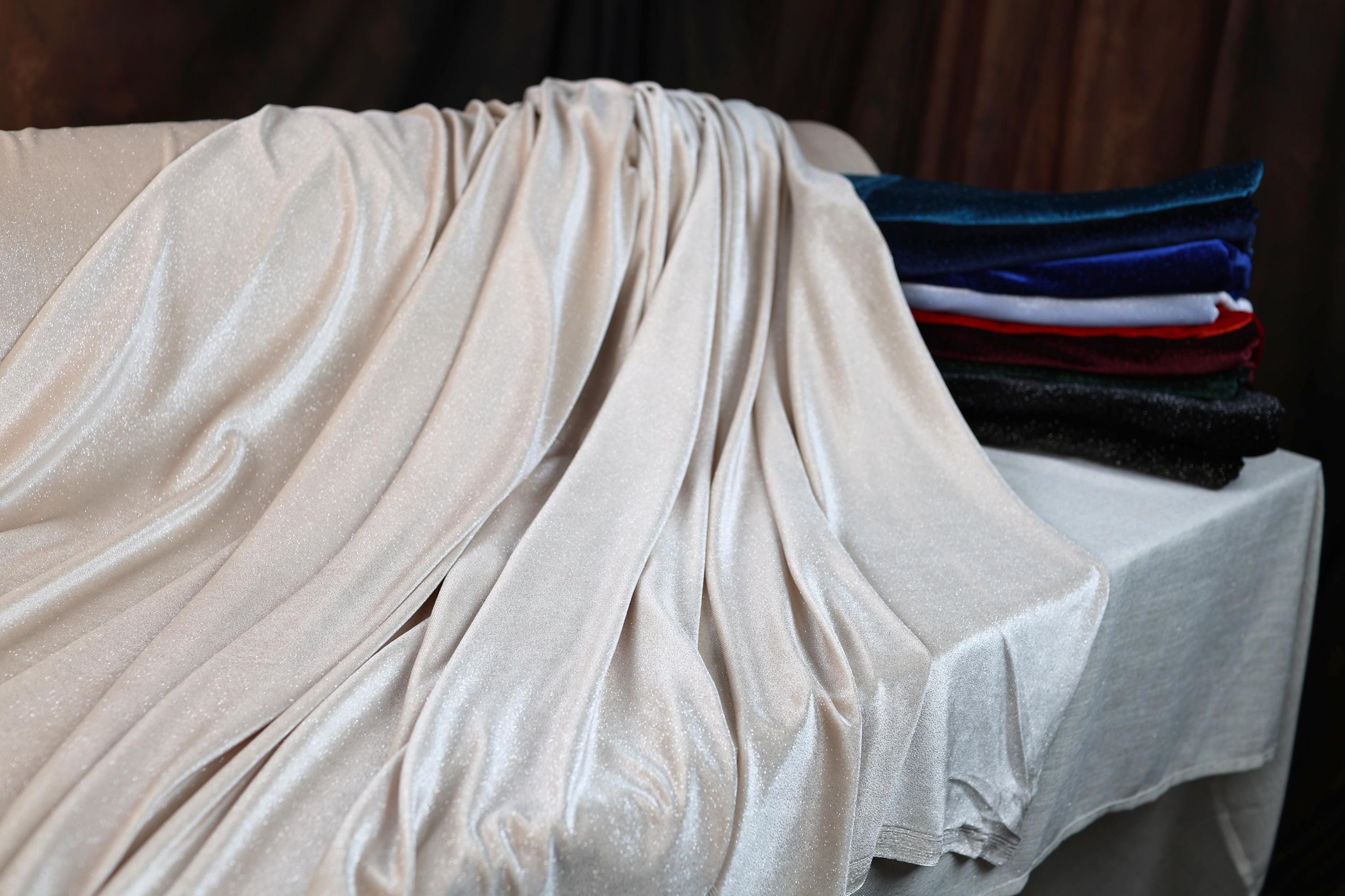 a bed covered in a white sheet next to a wooden wall