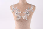 A mannequin with two white floral lace pieces sewn onto its shoulders.