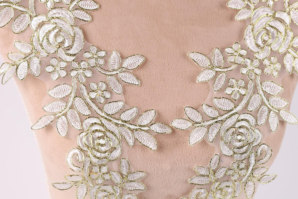 a close-up view of a delicate, intricate piece of embroidered fabric with a floral pattern. The fabric appears to be made of a soft, light-colored material, possibly cotton or a similar natural fiber. The embroidery is composed of numerous small, white flowers and leaves, arranged in a symmetrical and visually appealing manner. The overall composition of the image is focused on the intricate details and craftsmanship of the embroidered fabric.