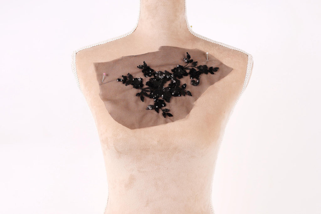a mannequin with a piece of fabric or material attached to its chest area, featuring a black floral design.