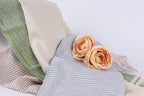 two pink roses resting on a blue and white striped fabric.