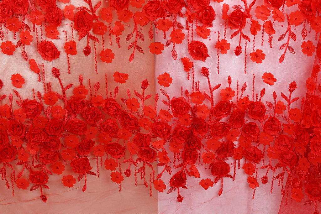 a close-up view of a fabric with a floral pattern of red roses and leaves. The fabric appears to be a sheer material, with the red flowers and leaves hanging down in a decorative manner.