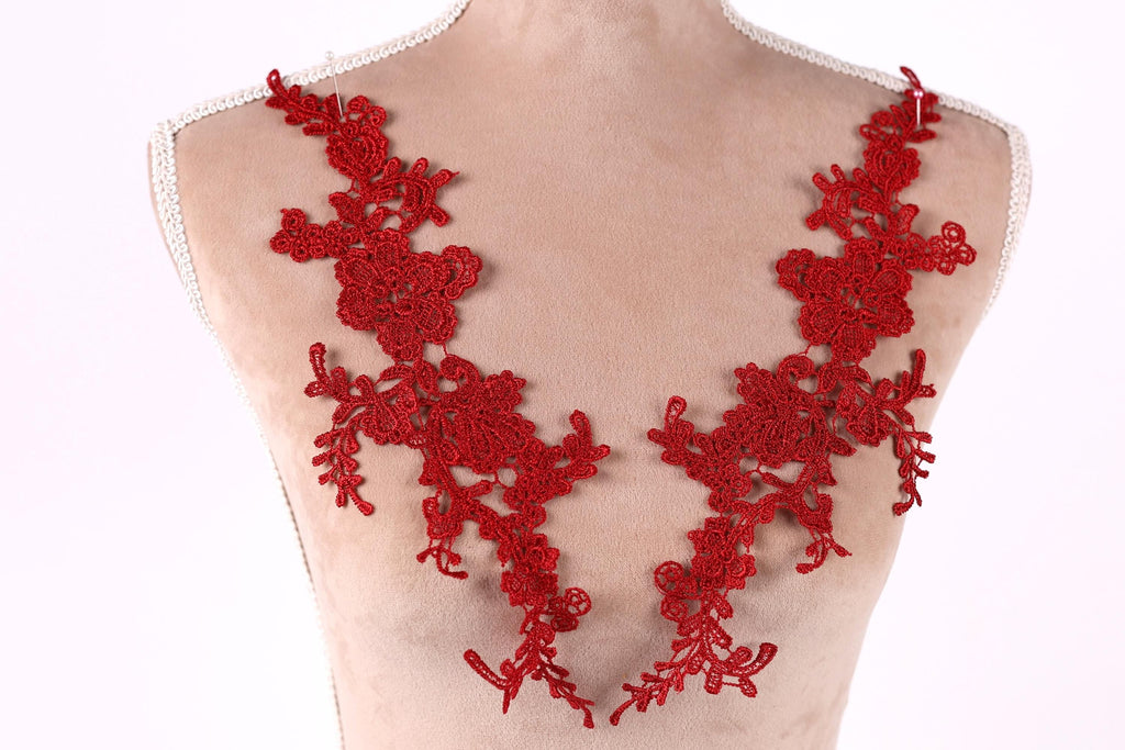 A mannequin wearing a red lace necktie with intricate floral patterns.