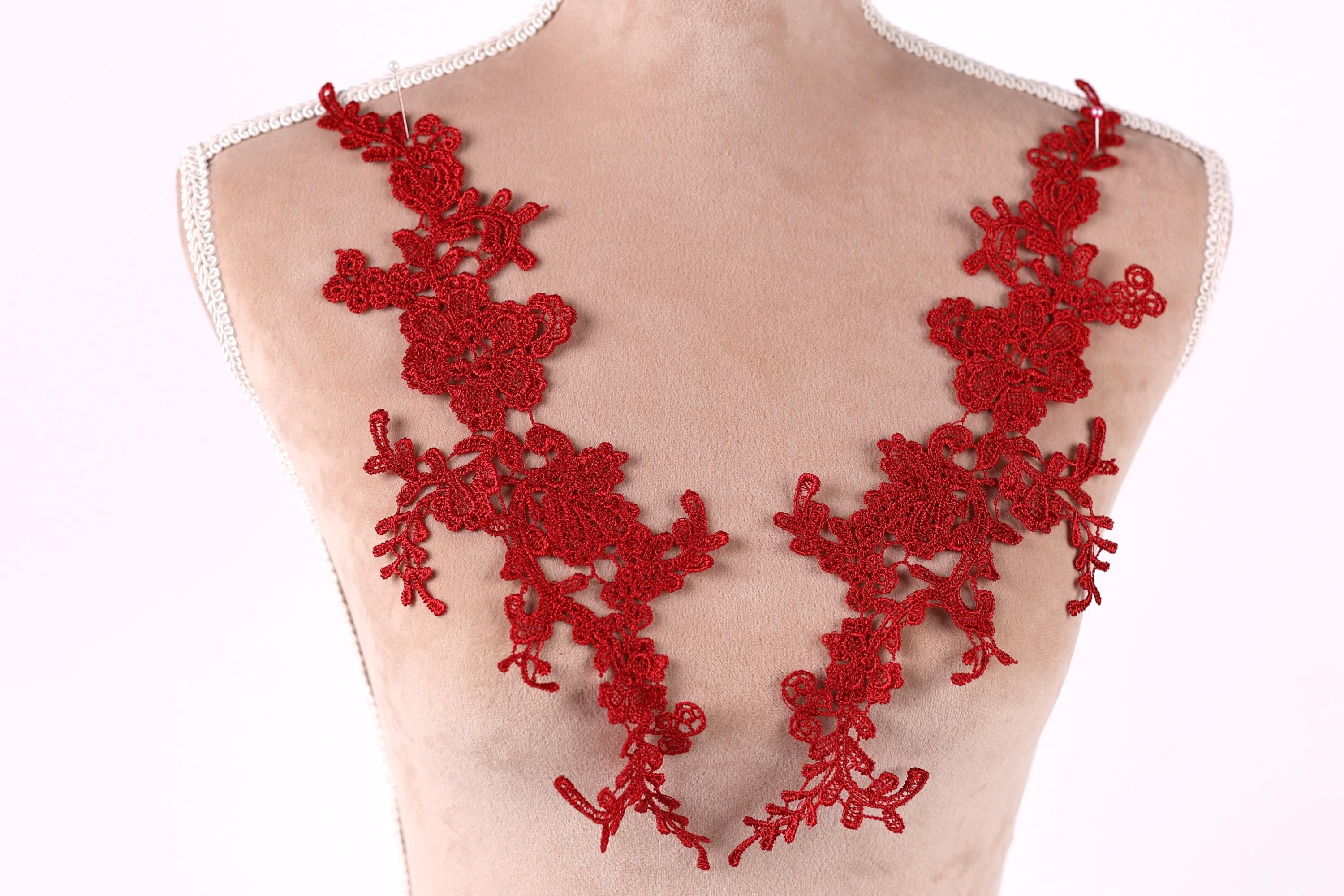 A mannequin wearing a red lace necktie with intricate floral patterns.