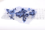 a piece of fabric with blue sequin flowers and leaves, placed on a transparent surface.