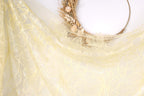 a decorative arrangement of a yellow fabric with a floral pattern, a wreath made of dried flowers, and a white circular frame.