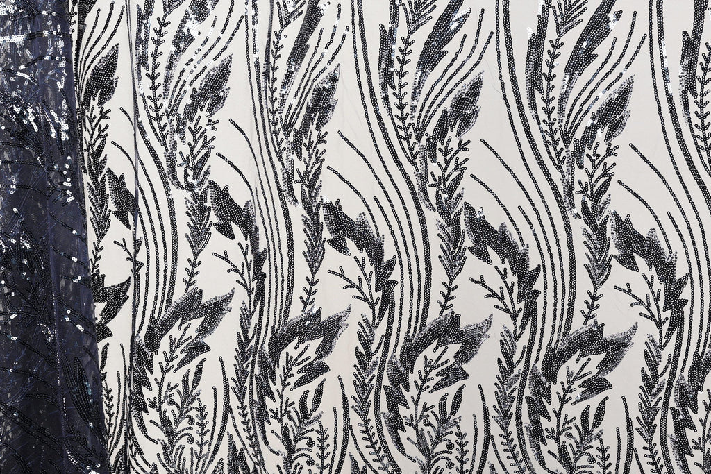 a close-up view of a fabric with a repeating pattern of black and white lines and shapes, resembling a floral or leaf-like design.