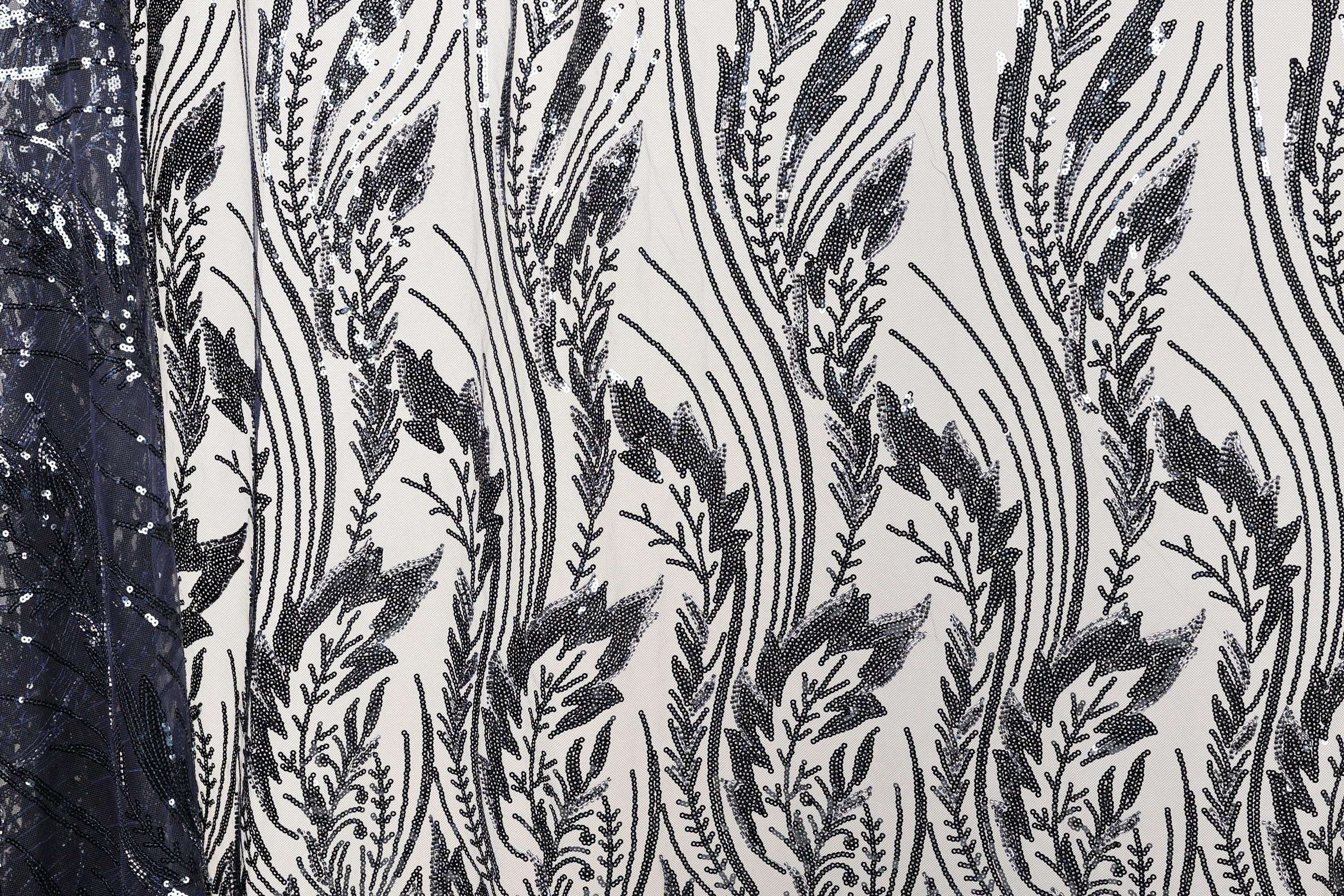a close-up view of a fabric with a repeating pattern of black and white lines and shapes, resembling a floral or leaf-like design.