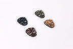 Four rhinestone-encrusted skull-shaped buttons in various colors, including black, blue, brown, and orange, arranged on a white background.