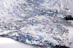 The image is a close-up view of a fabric with a complex, intricate pattern of blue and silver sequins and beads. The fabric appears to be a sheer or sheer-like material, with the colors and patterns creating a visually striking and textured appearance.