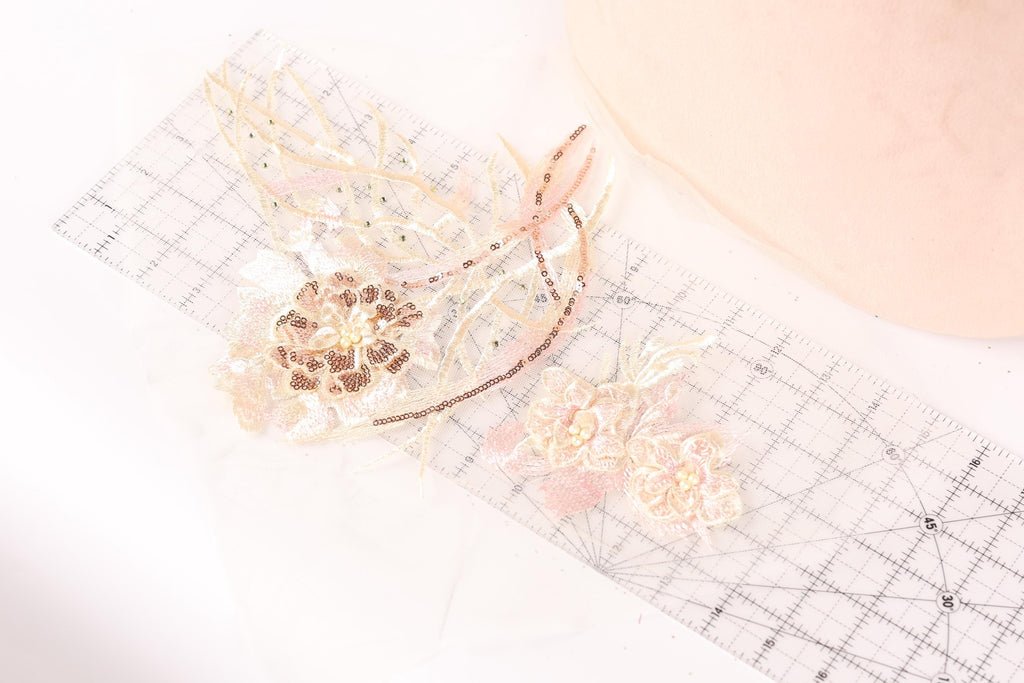 a close-up view of a clear ruler with various decorative elements, including a flower-shaped object and a butterfly-shaped object, placed on a white surface.