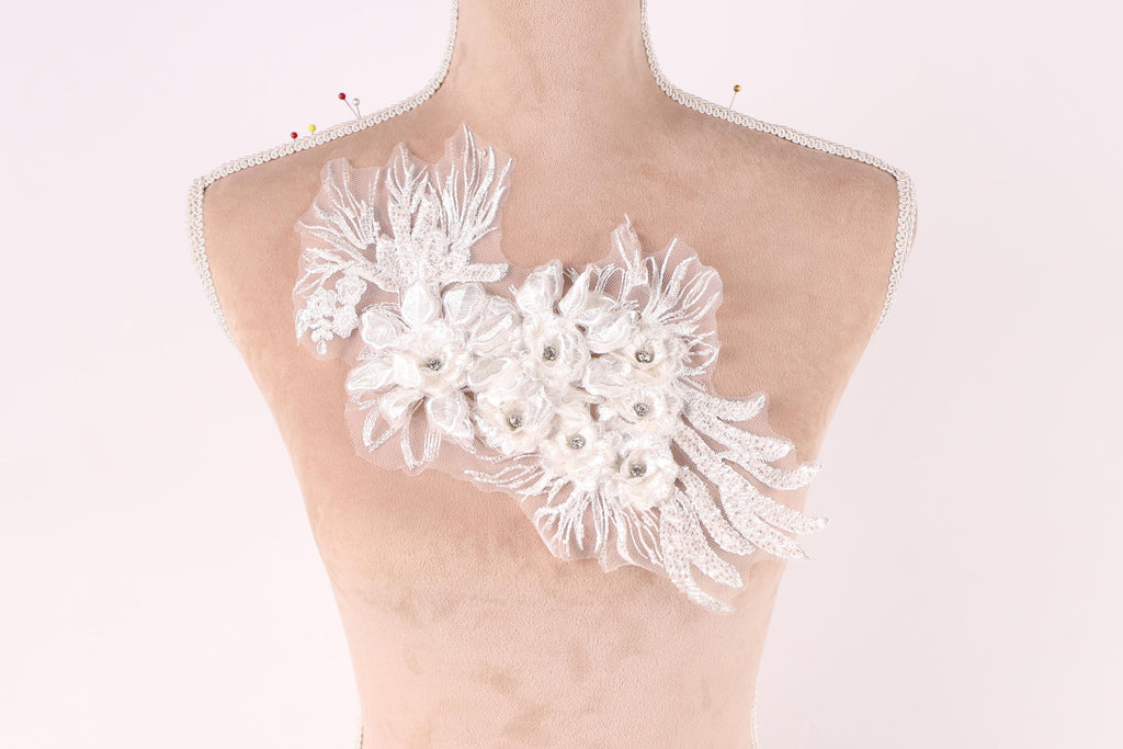 A mannequin bust with a decorative white lace flower embellishment on the shoulder.