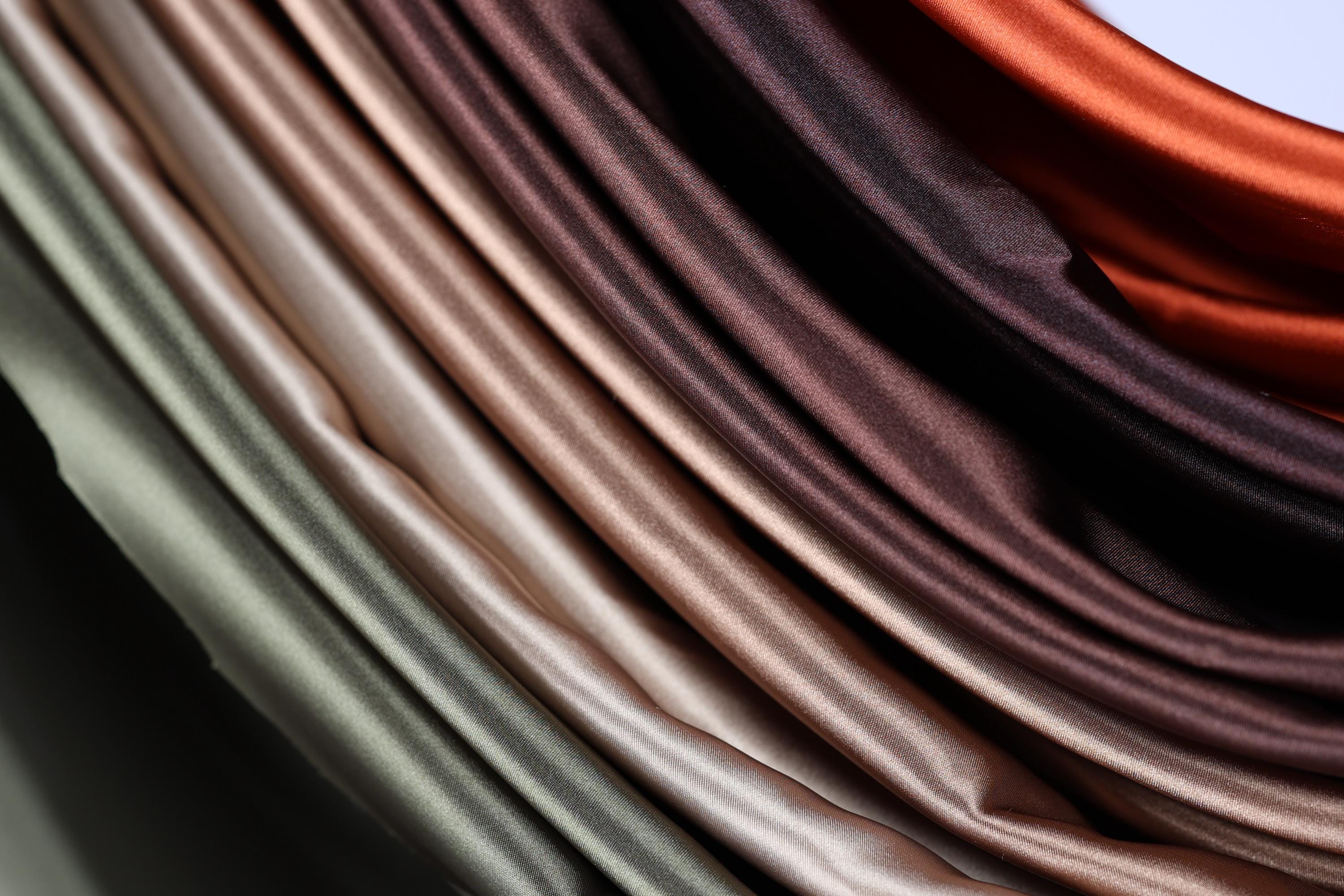 a close-up view of a variety of colorful satin fabric, with different shades of brown and orange.