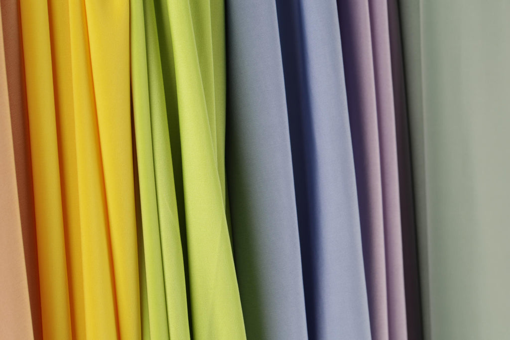 A row of colorful fabric swatches in various shades of yellow, green, blue, and purple.
