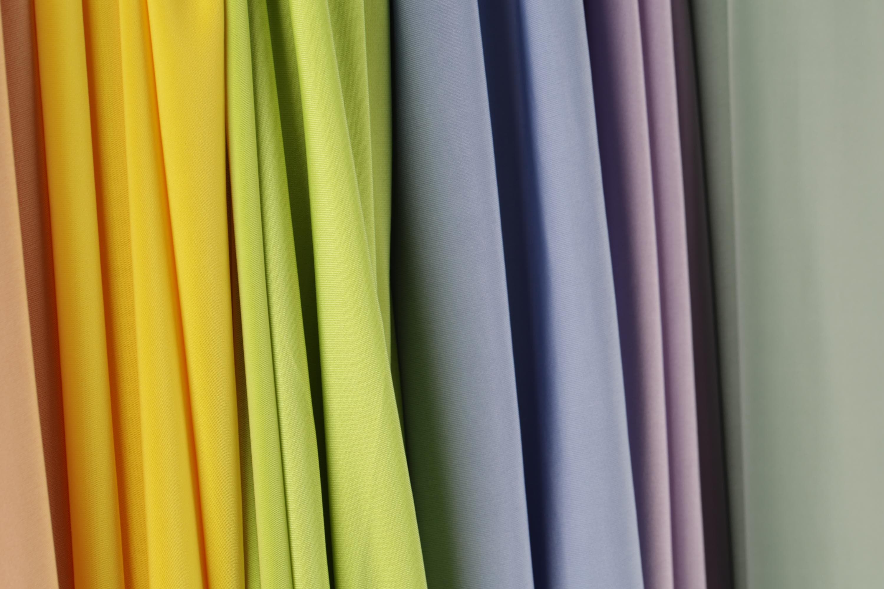 A row of colorful fabric swatches in various shades of yellow, green, blue, and purple.