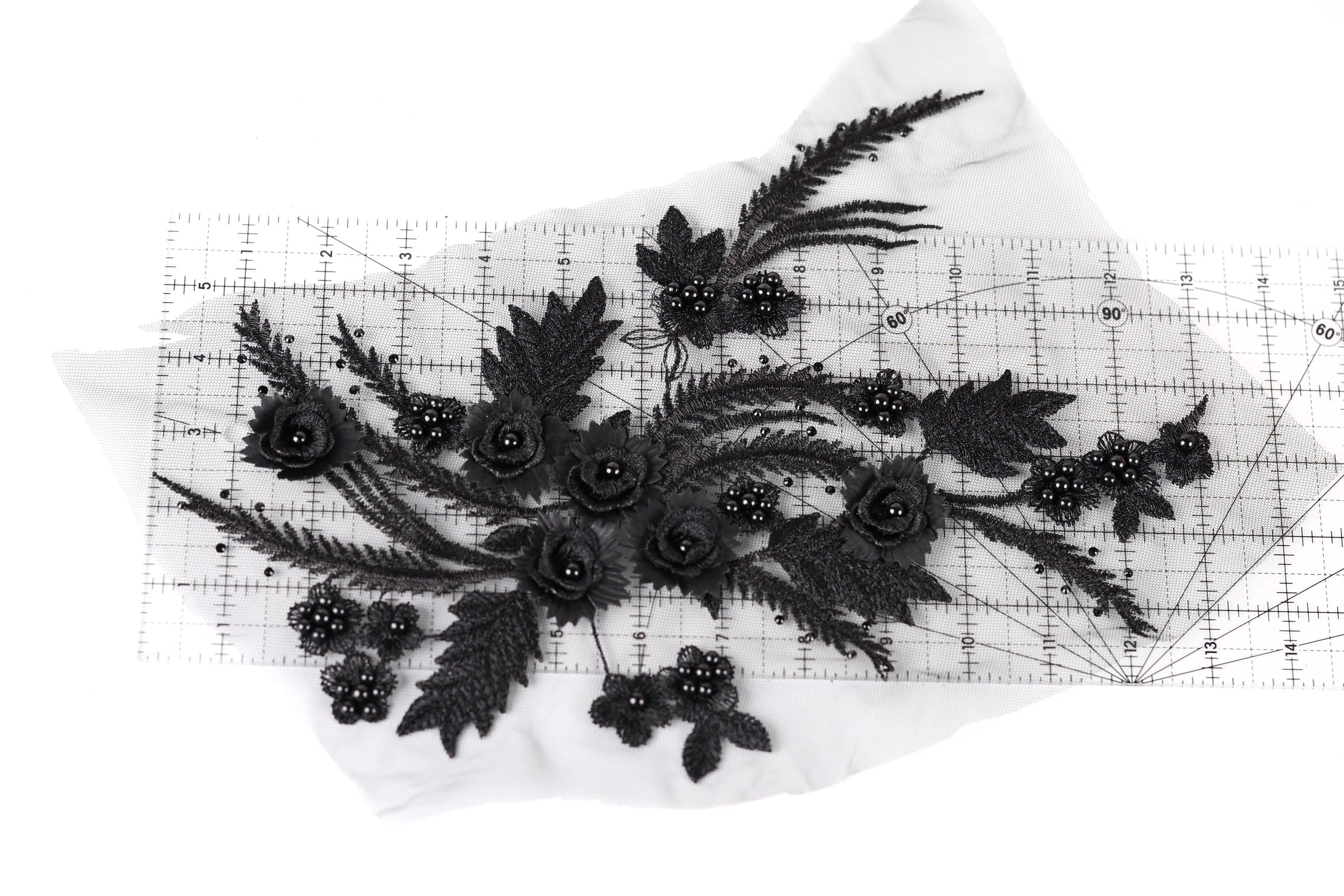 a close-up view of a black lace flower design with numerous black beads and leaves attached to it.