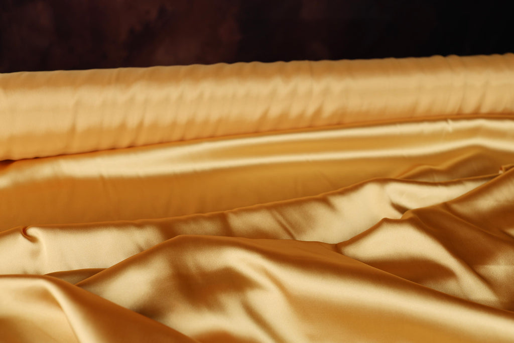 a close up of a bed with a gold comforter